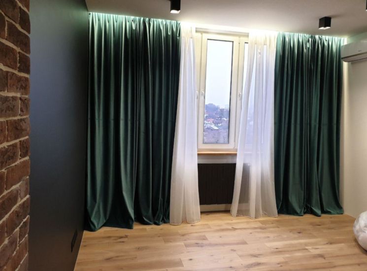 Изумрудные бархатные шторы и белый тюль в интерьере гостиной